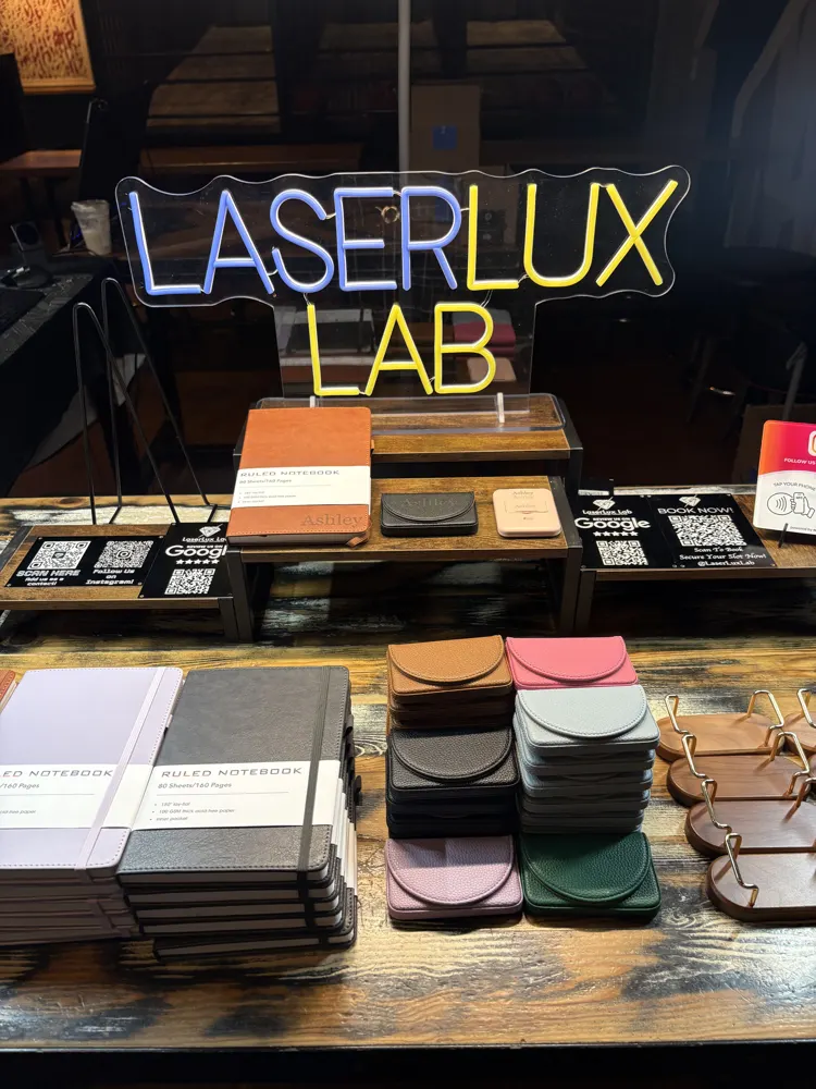 LaserLux Lab neon sign and engraved samples on a booth table at an event